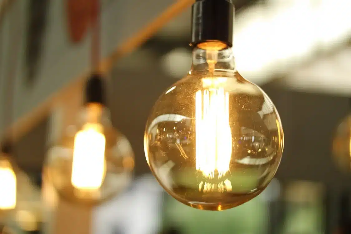 Lit light bulb hanging, symbolizing environmental commitment in a modern space.